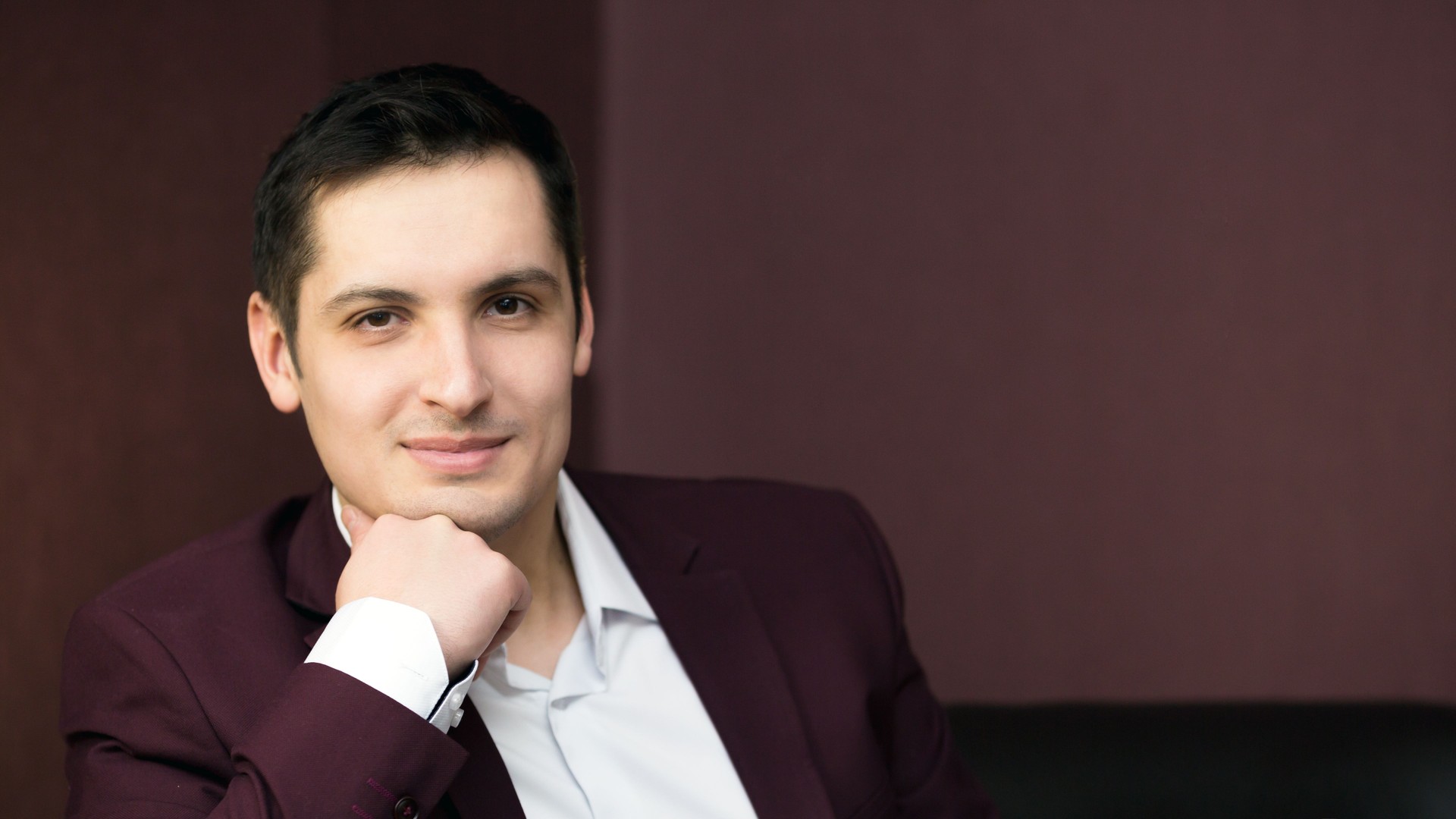 Handsome brunette man sitting on the sofa, a place for an inscription.